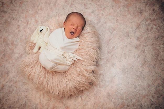 Newborn baby wrapped in a blanket sleeping in a basket. 