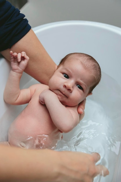 Newborn in the bathtub held by her mother