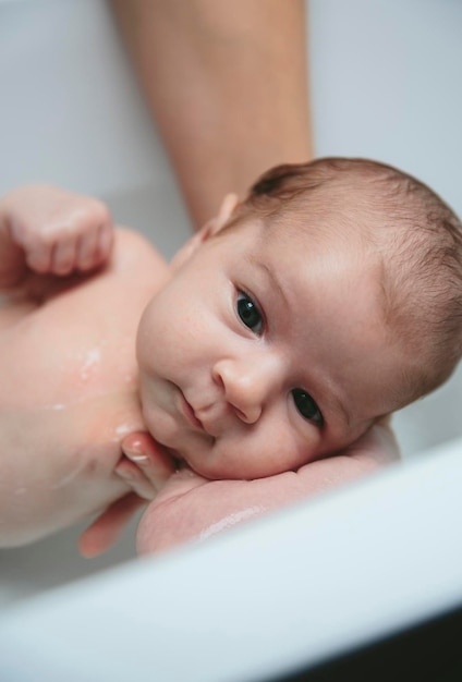 Newborn in the bathtub held by her mother