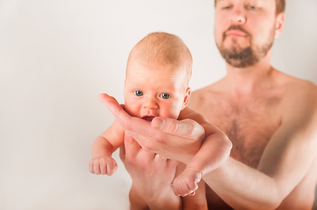 Newborn on the bed with his father close-up. The concept of the relationship of children and parents from birth.