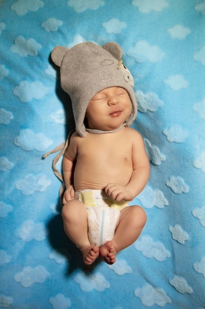 a newborn in a big hat with an airplane on a blue blanket sleeps