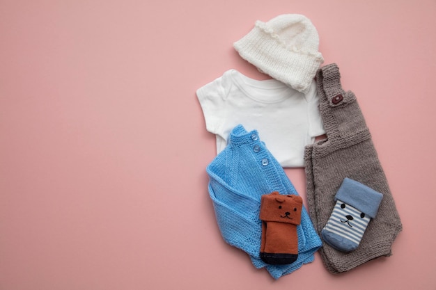 Newborn child clothing layout on a pastel pink background