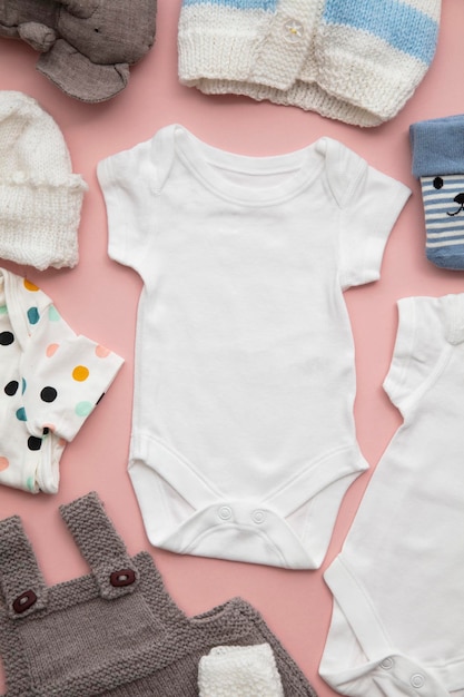 Newborn child clothing layout on a pastel pink background