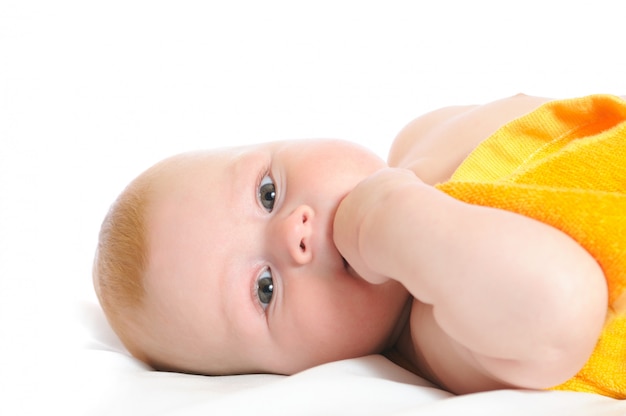 Newborn covered with a yellow towel lying in bed