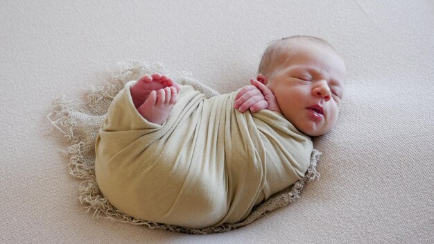 Photo newborn in a crib in a green winding and cap