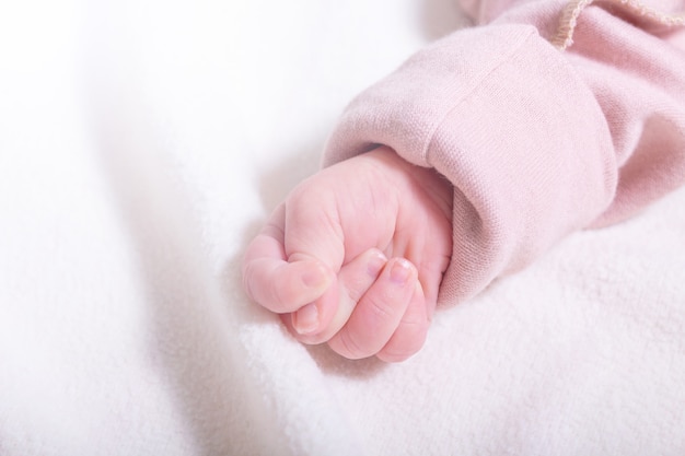 Новорожденная девочка кавказской рука в кулак