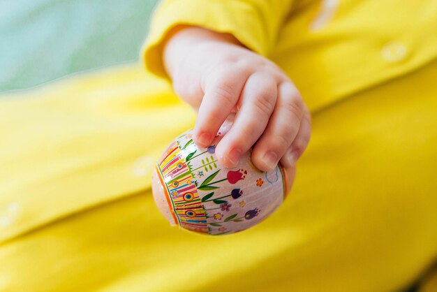 The newborn holds a colorful Easter egg in his hand Easter hunting concept