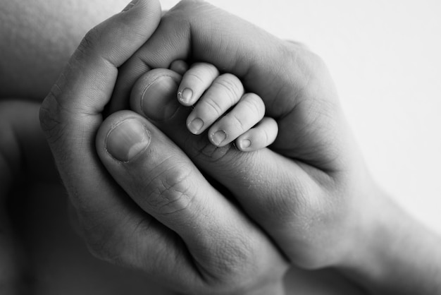 A newborn holds on to mom39s dad39s finger Hands of parents and baby close up A child trusts and holds her tight Tiny fingers of a newborn Black and white macrophoto Concepts of family and love