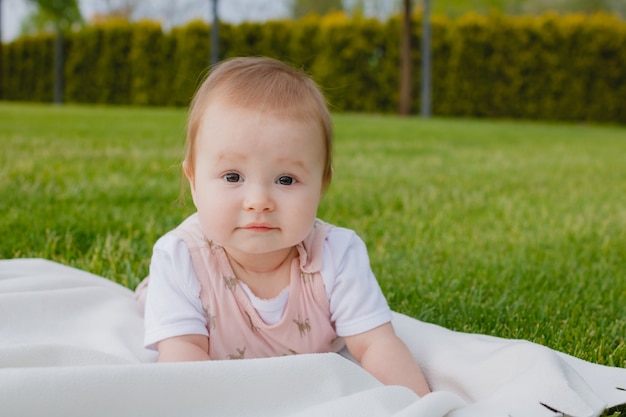 newborn nursing baby girl lying on a white plaid on the grass in a park