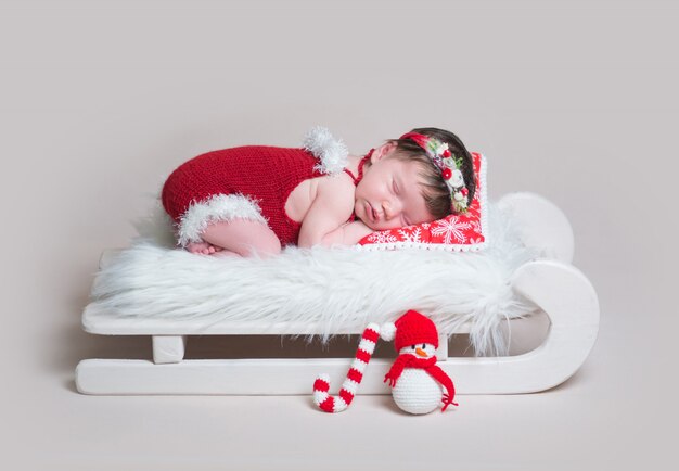 Newborn in Santa's bodysuit sleeping