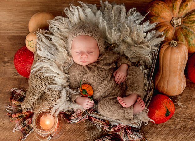 Photo newborn sleeping framed by orange pumpkins