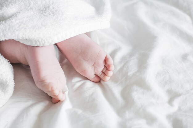 Newborn toddler boy legs with towel on bed