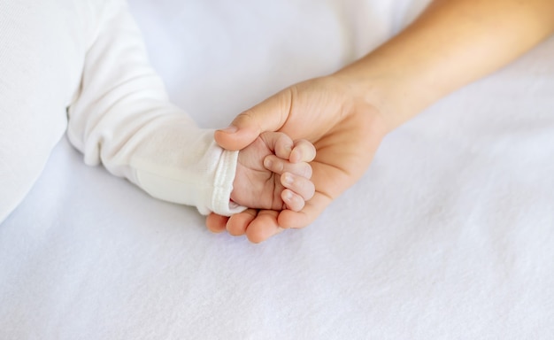 Newborn toddler holds his sister's hand