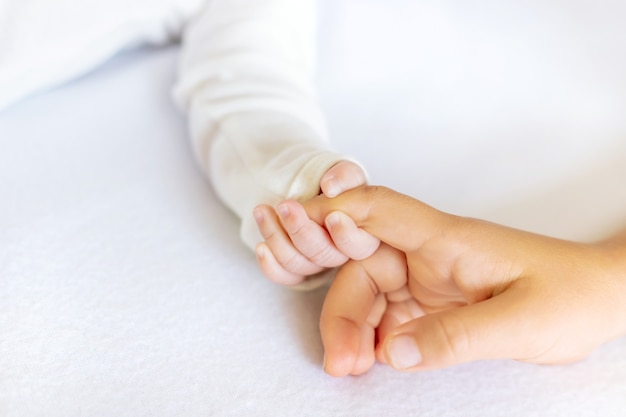 Newborn toddler holds his sister's hand