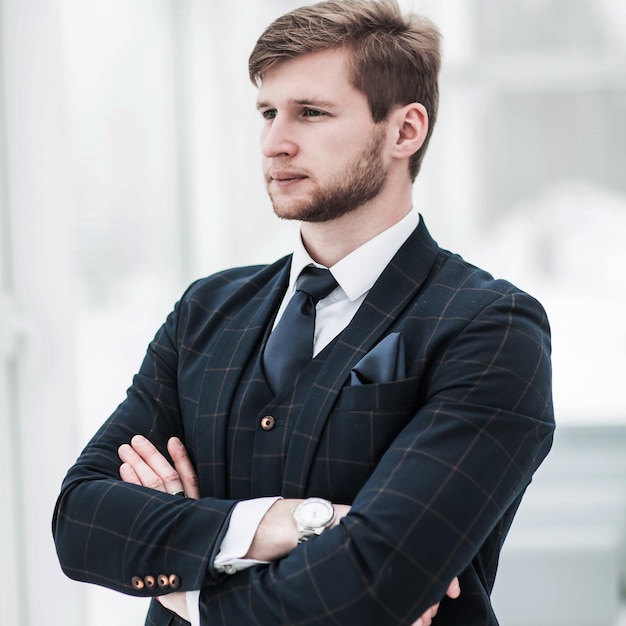 Newcomer businessman in a business suit stands near the window