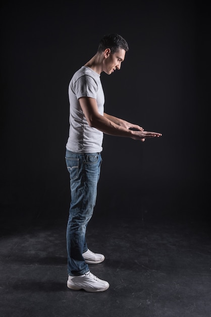 Newest innovations. Nice handsome smart man standing against black background and looking at the computer panel while working on it