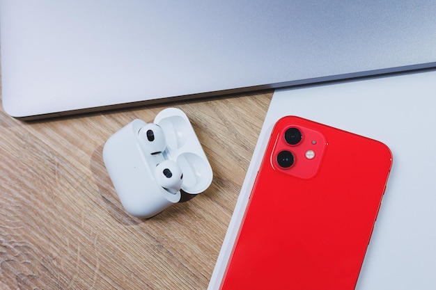 Newest red smartphone and wireless headphones in charging case\
on white background