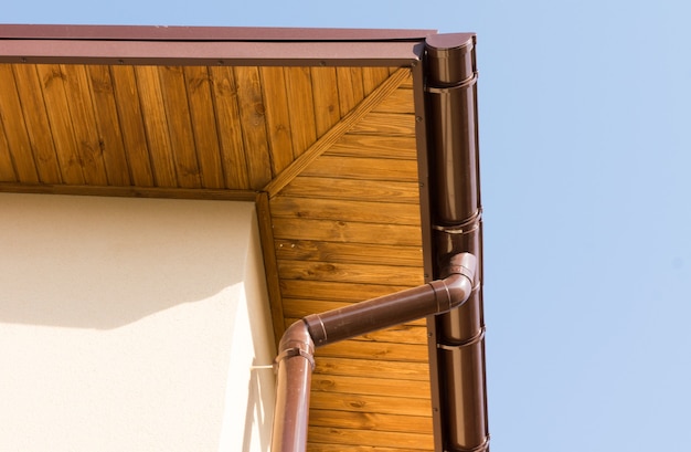 Photo newly installed guttering and drainpipe on the wooden eaves of a new build house under construction