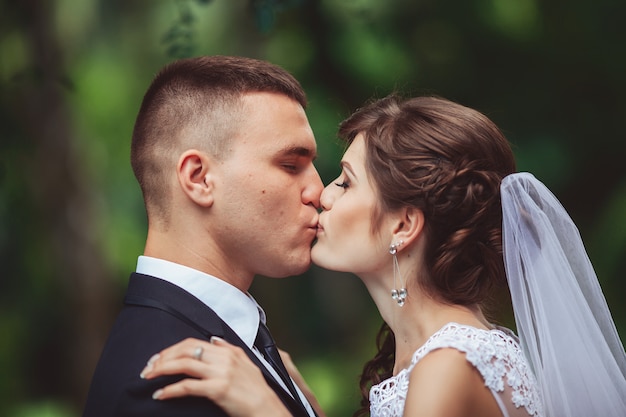 The newly married couple kissing at alley in park