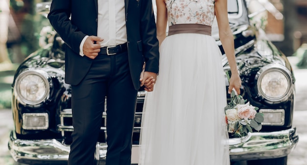 Newlymarried couple in front of a black classic car