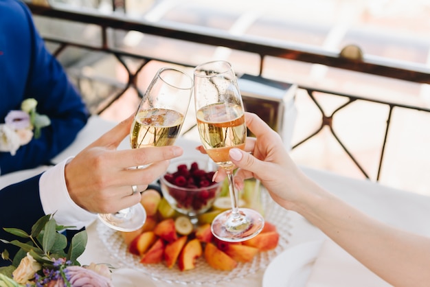 Newlywed bride and groom eating fruit and drinking champagne on their wedding day