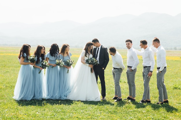 Newlywed couple, bridesmaids and groomsmen having fun outdoors