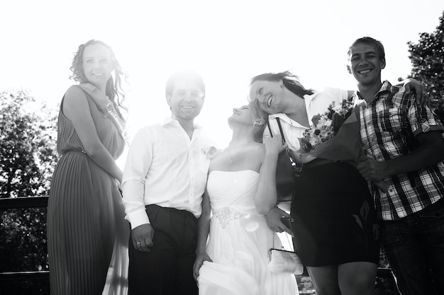 Photo newlywed couple with friends standing outdoors