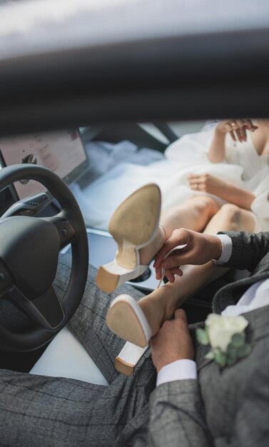 the newlyweds are in the car, the groom helps the bride with her shoes