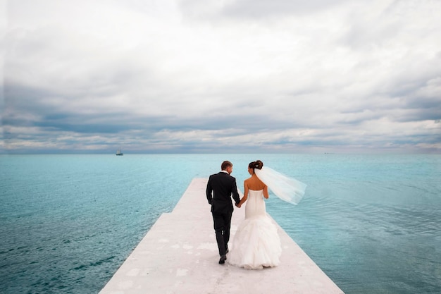 Newlyweds are walking on the sea berth