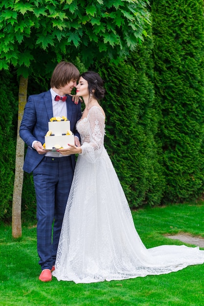 Newlyweds and bridesmaids have fun and eat wedding cake together in the fresh air on wedding banquet.