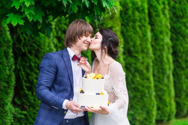 Newlyweds and bridesmaids have fun and eat wedding cake together in the fresh air on wedding banquet.