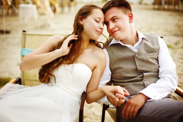 Newlyweds couple sitting near water on the beach