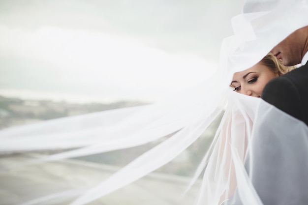 Newlyweds covered by the veil of the bride