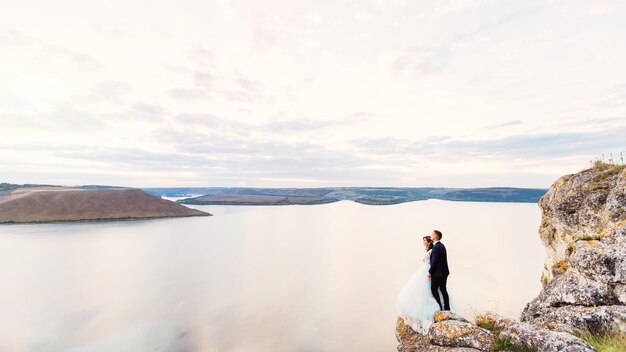 The newlyweds embraced on riverbank and the evening sky with clo