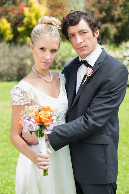 Newlyweds embracing each other looking at camera