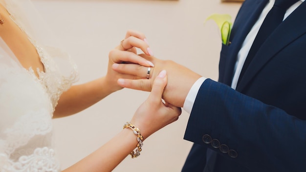 Newlyweds exchange rings groom puts the ring on the bride's hand in marriage registry office