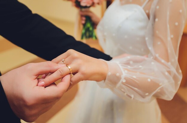 Newlyweds exchange rings groom puts the ring on the bride's hand in marriage registry office