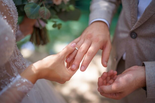 Foto gli sposi si scambiano gli anelli. lo sposo mette l'anello sulla mano della sposa.