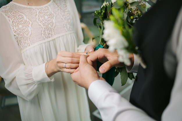 Newlyweds exchange rings in marriage registry office. wedding rings and hands of bride and groom.