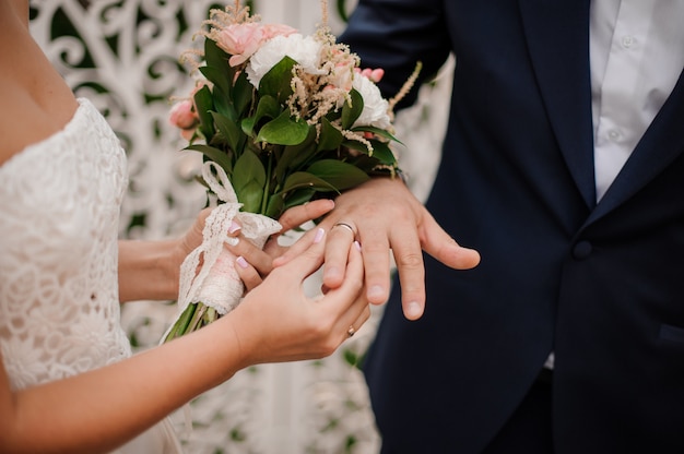 Sposi che scambiano anelli, sposa che mette l'anello sulla mano dello sposo