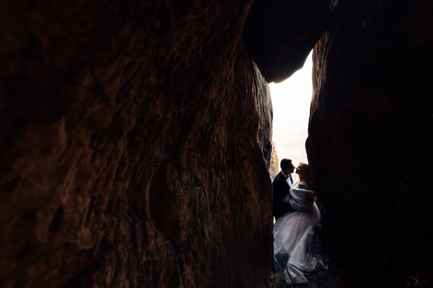 Молодожены в праздничных нарядах хотят поцеловаться на свадьбе в каменном тоннеле