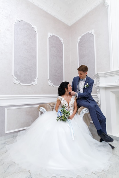 Gli sposi si guardano dolcemente. ritratto sposa e sposo abbracciando in una cerimonia di nozze in un interno elegante. felice giornata di diserbo