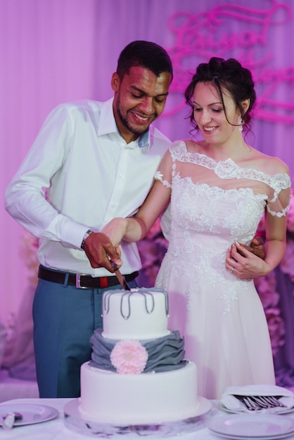 Newlyweds happily cut, laugh and taste the wedding cake