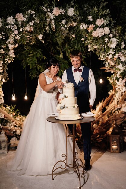 Newlyweds happily cut, laugh and taste the wedding cake