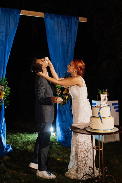 Newlyweds happily cut, laugh and taste the wedding cake
