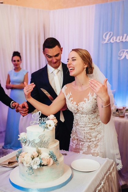 Newlyweds happily cut, laugh and taste the wedding cake