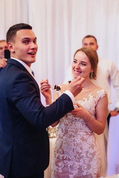 Newlyweds happily cut, laugh and taste the wedding cake