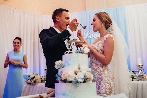 Newlyweds happily cut, laugh and taste the wedding cake