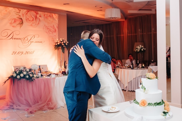 Newlyweds happily cut, laugh and taste the wedding cake