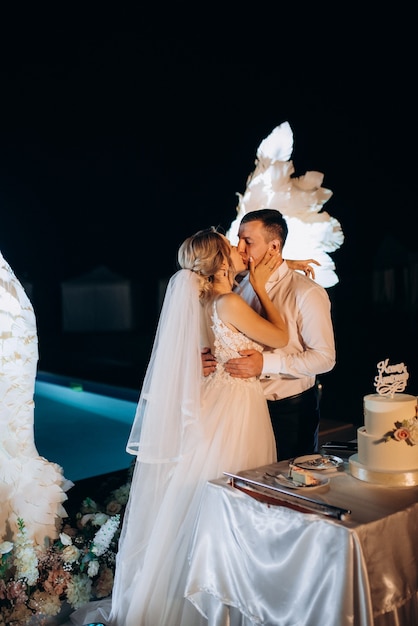 Newlyweds happily cut, laugh and taste the wedding cake